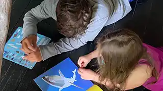 two autistic children coloring during a therapy session.